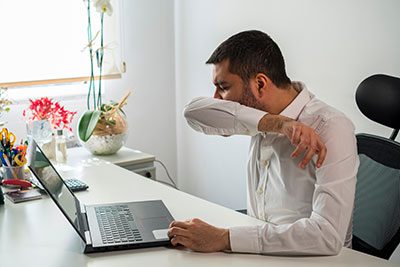 man sneezing into elbow